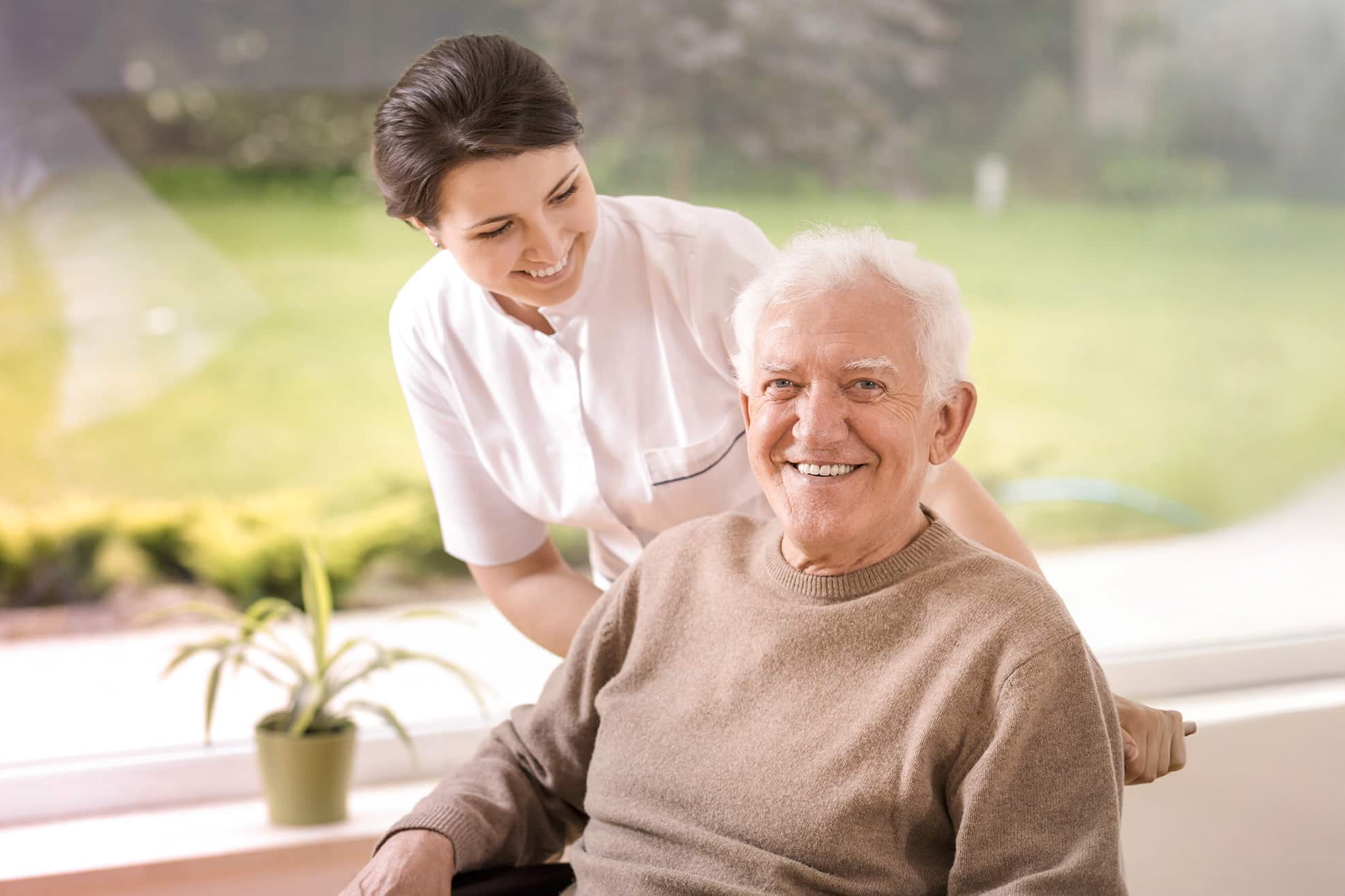 Freundliche Pflegekraft unterstützt lächelnden älteren Mann mit Behinderung
